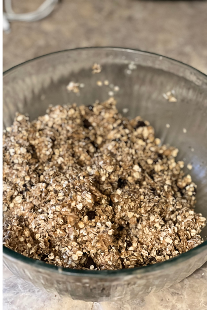 Mixing bowl sitting on a counter top containing mixed ingredients of recipe. 